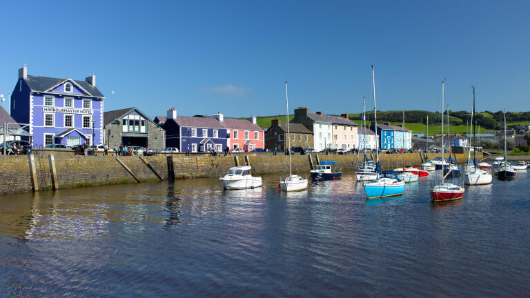 A view of the Harbourmaster Hotel, Aberaeron, with boats moored in the harbour.