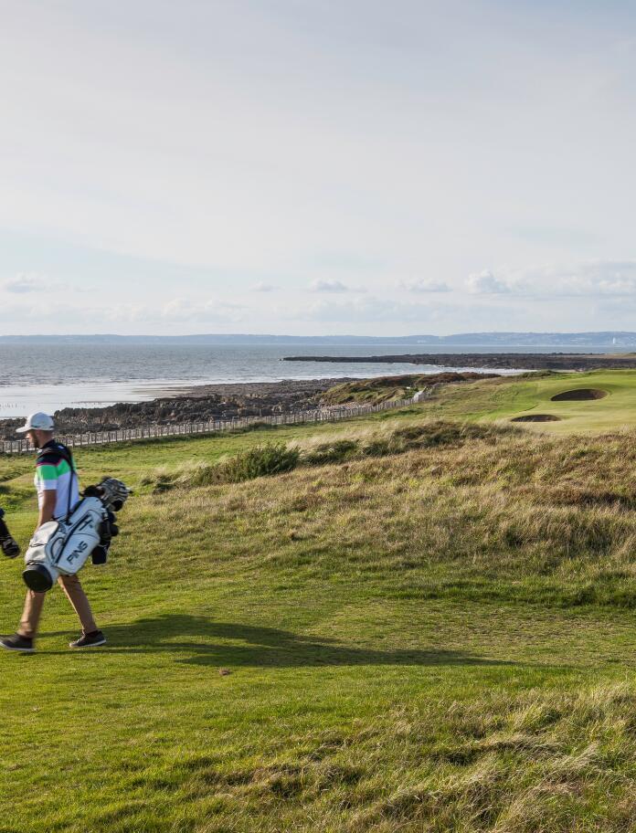 Golfers on Royal Porthcawl golf course by the sea.