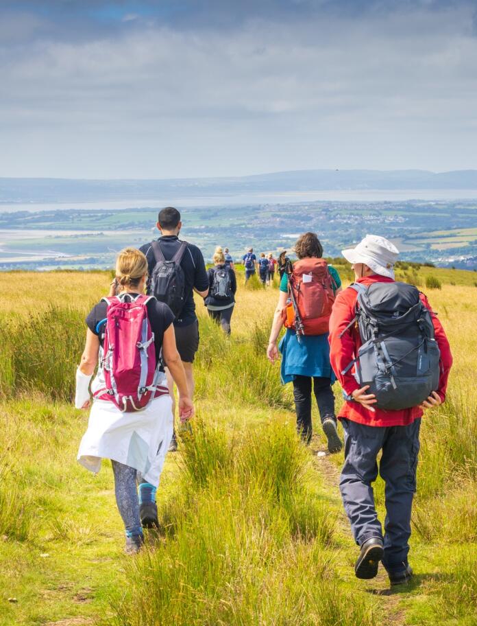 A group of walkers on a mountain with coastal views beyond.