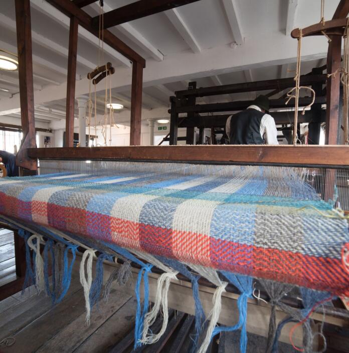 A blanket being weaved on a loom.
