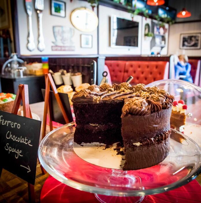 A chocolate cake on a cake stand on display in a cafe.