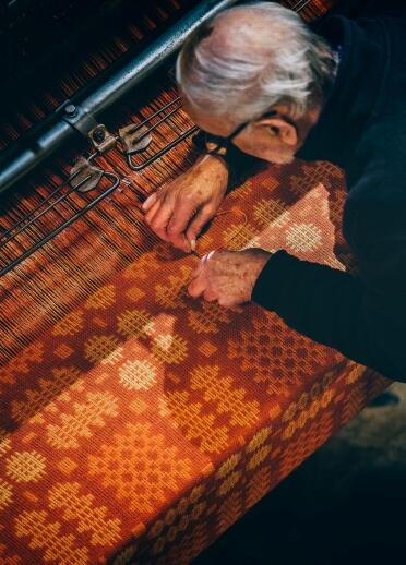 A weaver creating a Welsh blanket on a loom.