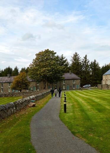 People walking passed stone cottages at a Welsh language centre.