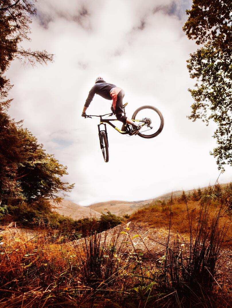 A mountain biker performing a dramatic jump in a forest